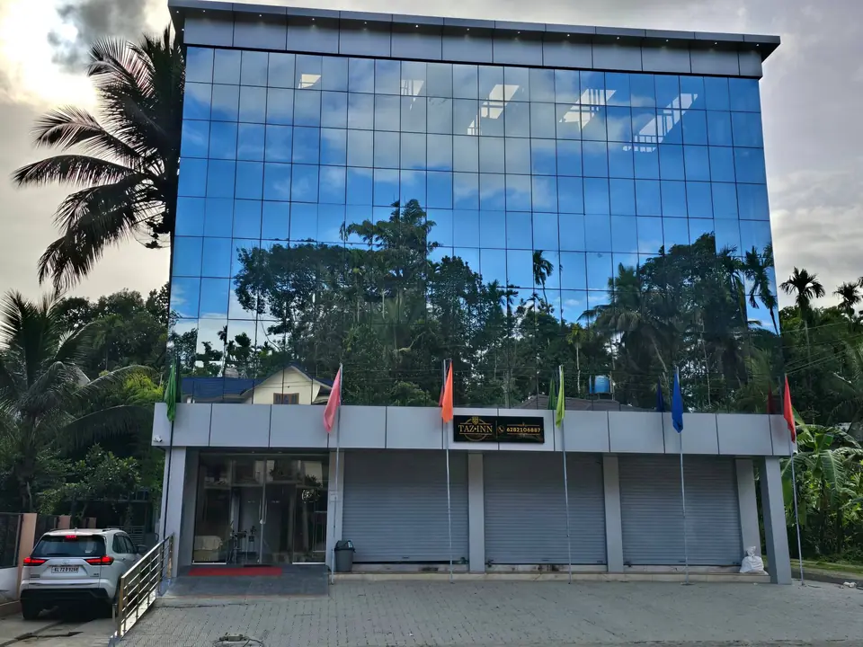 The glass front of Tazinn Stay reflecting palm trees